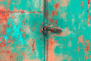Old rusted grungy metal garage door with latch and padlock