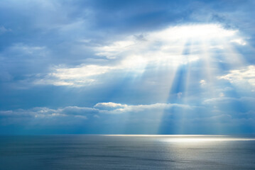 sea scape under a dense cloudy sky with rays pushing through, summer sea background