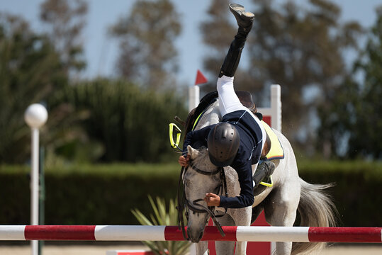 Horse show jumping accident, young rider falling from horse during a competition