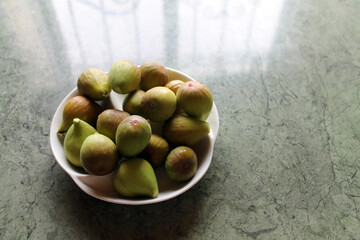 Fresh ripe figs on a white plate on a stone background. The concept of healthy eating.