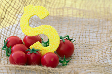 New harvest costs and expences concept: tomatoes with yellow dollar sign on jute and white...