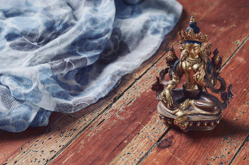 Figura budismo de tara verde sobre suelo de madera y tela de fondo. - obrazy, fototapety, plakaty