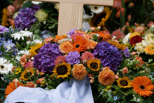 flowers and funeral wreaths on a new grave with wodden cross