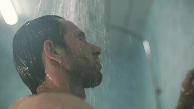 guy washes in the shower room after a soccer match after a workout, after training water runs down his face splashing water
