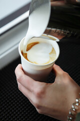 Barista draws milk over a coffee - making latte art for cappuccino