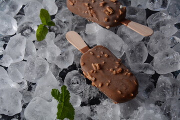 Popsicle chocolate ice cream with almonds on ice cubes background