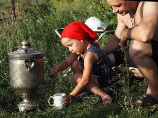 A little girl, while relaxing with her dad in nature, learns to pour tea from a samovar. Joint family affairs and leisure.