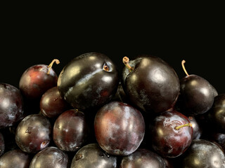Blue plums on a black background. Heap of ripe plums in a plate. Fruit tree fruit.