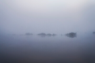 Morning fog before sunrise over a forest lake