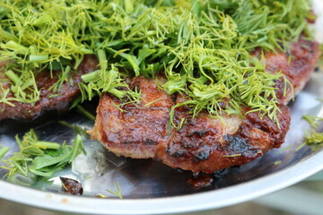 BBQ baked pork sprinkled with dill and parsley. Outdoor cooking concept. Selective focus.
