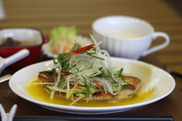 Close up of a set of delicious grilled fish served with vegetable salad topping and sweet sauce, Hiroshima, Japan, soft focus