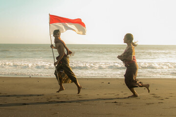 Two Indonesian Youth Wearing Balinese Traditional Clothes while Holding Indonesian Flag