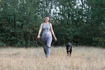 Young attractive sport girl walking with black Labrador in park. Healthy lifestyle. Walk with favorite pet in wood.