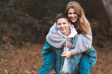 Happy teen boy and girl 15-16 year old having fun outdoors over autumn nature background. Looking...