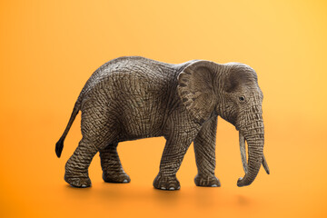 Fototapeta premium Miniature elephant animal toy on orange background
