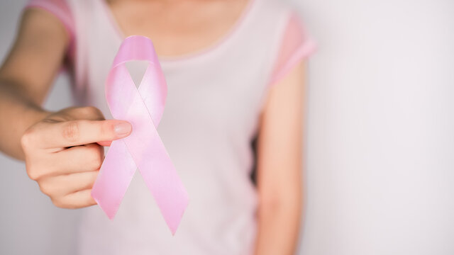 Woman wearing a white t-shirt is hand holding pink ribbon with white background, Breast cancer symbol, Breast cancer awareness month. Important days in October