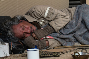 Homeless man sleeps on a pavement.