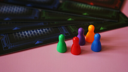 Colored board game figures on pink background