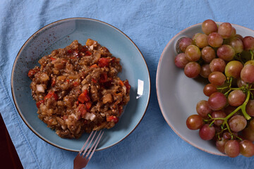 Baked eggplant and peppers salad on a blue plate. Grapes on a blue plate.