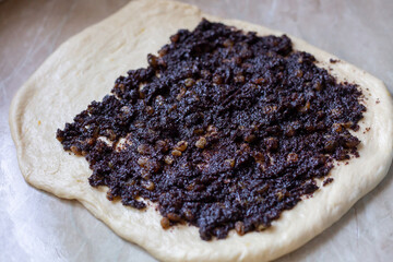 Spreading poppy seed and raisins topping with fork on yeast dough for pie. Poppy seeds and raisins filling for pie
