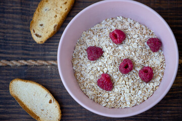 Oatmeal porridge with raspberries and toasts on black background. Healthy lifestyle. Ecofriendly. soft focus