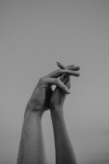intertwined hands of a man and a woman on a gray background,