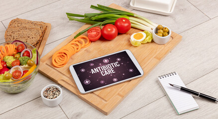 ANTIBIOTIC CARE concept in tablet pc with healthy food around, top view