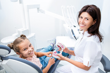 Positive dentist and little girl in a dentist's office. Kid teeth treatment