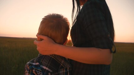 happy family mom and son hugs son over the shoulders close-up teamwork. mother and boy kid together stand with their backs watching the sunset. parent girl and child happy childhood. lifestyle happy