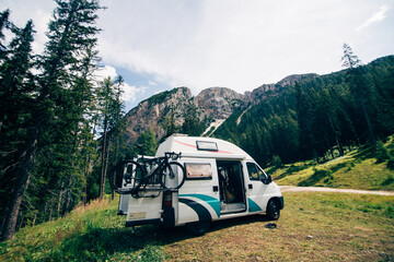 Cute vintage camper van or camping RV parked in wild camping spot in mountain forest. Bicycle on...