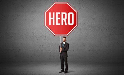 Young business person holding road sign with HERO inscription, new rules concept