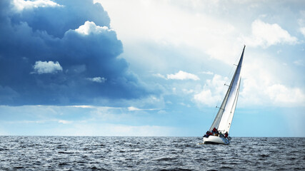 Sailing yacht regatta. Modern sailboat racing through the waves. Dramatic sky before the...
