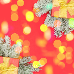 Christmas card composition with golden bokeh light, gifts and Xmas tree branch on red background