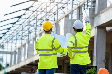 Structural engineer and architect dressed in green work vests work in progress of construction...