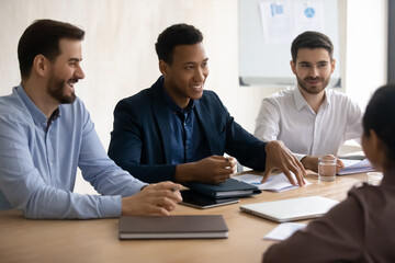 Happy african american businessman with european colleagues holding negotiations meeting, discussing partnership with multiracial people in office, professional communication, successful collaboration