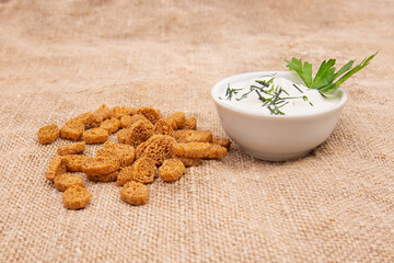 a stack of croutons breadcrumbs and a bowl of green onions and sour cream are spread out on the burlap