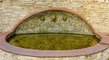 Fountain made of stone with taps from the wall.