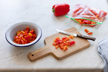 chopped fresh bell peppers on a wooden cutting board. preparation of organic vegetables for freezing. light background. copy space