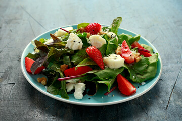 Goats cheese and strawberry summer salad served with nigella and sesame seeds drizzled with runny honey