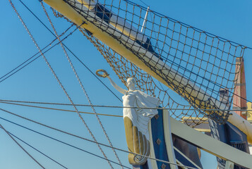 The figure of a woman on the bow of an ancient sailboat. - obrazy, fototapety, plakaty