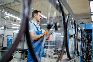 Worker at the assemly line makes bicycle wheels