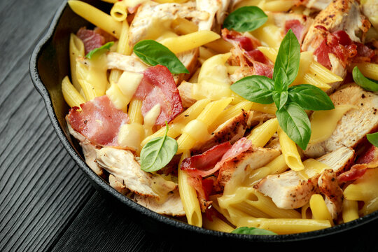 Chicken, bacon Penne pasta with cheese and basil in iron cast. healthy food.