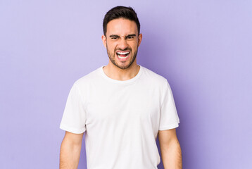 Young caucasian man isolated on purple background shouting very angry, rage concept, frustrated.