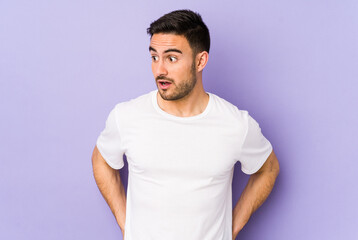 Young caucasian man isolated on purple background being shocked because of something she has seen.