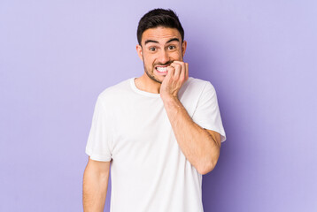 Young caucasian man isolated on purple background biting fingernails, nervous and very anxious.