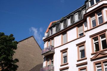 Schöner heller Altbau mit Balkons und Dachgauben vor blauem Himmel im Sommer bei Sonnenschein im...