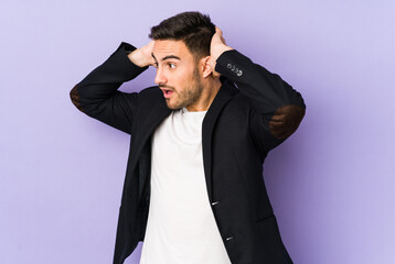 Young caucasian man isolated on purple background screaming, very excited, passionate, satisfied with something.