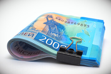 A rolled up bundle of Russian bills of 2000 rubles. Money tied with an office clip and lie on a white background with vignetting. Child support allowance and unemployment benefit in Russia. Macro