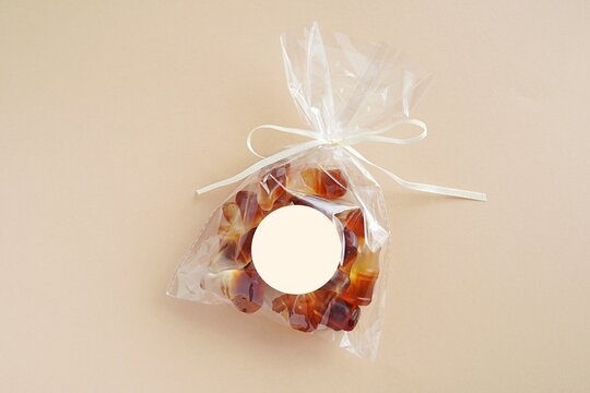 Party Favor Bag And Empty Round Sticker Mockup, Blank Sticker For Design, Light Brown Background.