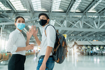 two attractive asian businessman and businesswoman wear face mask protection hand gesture wave greeting and goodbye social distancing in departure airport terminal